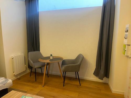 a table and chairs in a room with a window at Studio central et chaleureux in Belley