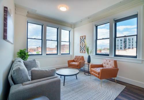 a living room with a couch and chairs and windows at The Standard Downtown Columbus in Columbus