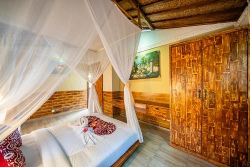 a bedroom with a canopy bed with a doll on it at Yoga Maya Villa in Gianyar