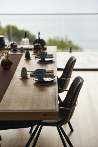 a long wooden table with chairs and bowls on it at Waterfront 'Tupelo' with Sauna on Primrose Point in Primrose Sands