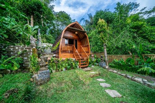a wooden cabin in a garden with a fence at Yoga Maya Villa in Gianyar