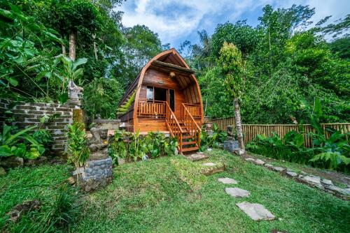a wooden cabin in a garden with a fence at Yoga Maya Villa in Gianyar