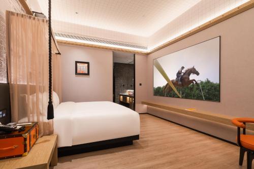 a bedroom with a bed and a picture of a horse on the wall at Arthur Hotel Liwan COCO Park Dongsha Metro Guangzhou-24H Coffee & Low Tea & Free Shuttle Bus For Canton Fair By Paco in Guangzhou