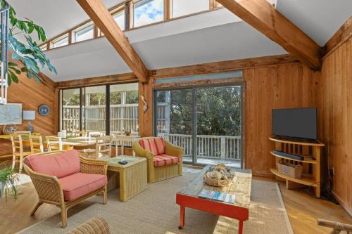 a living room with wooden walls and a ceiling with windows at Beach Grove home in Pine Knoll Shores