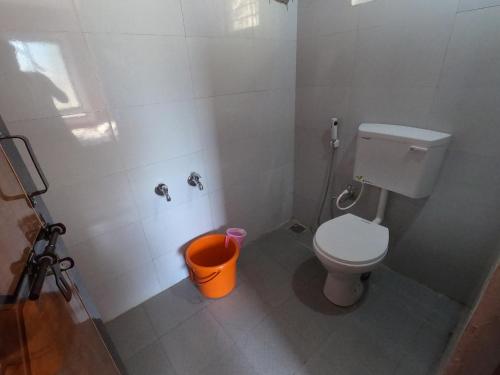 a bathroom with a toilet and a trash can at Hallimane Homestay in Udupi