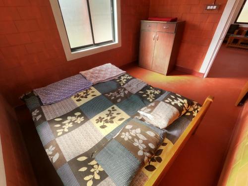a bed with a quilt on it in a room at Hallimane Homestay in Udupi