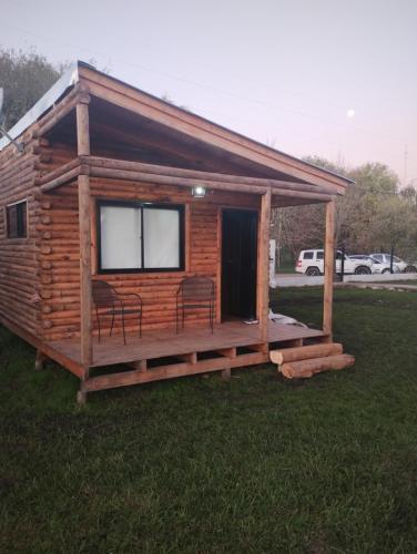 a log cabin with two chairs and a porch at Cabañas Olavarría in Olavarría