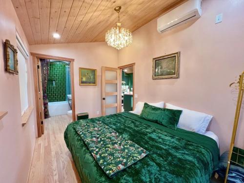 a bedroom with a green bed and a chandelier at The Perch- Hilltop Bungalow, Eagle Rock-near DTLA in Los Angeles