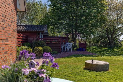 a garden with a bird bath and a cabin at Fewo-Inselblick in Nordstrand