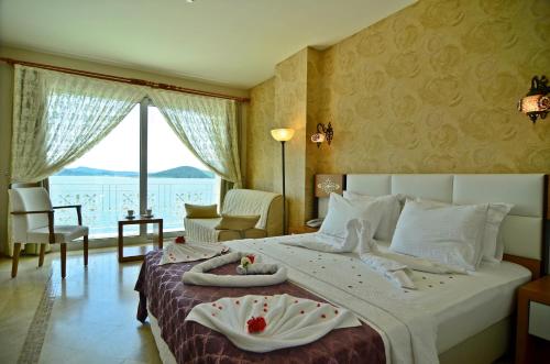 a bedroom with a large bed with a large window at Cunda Kivrak Hotel in Ayvalık