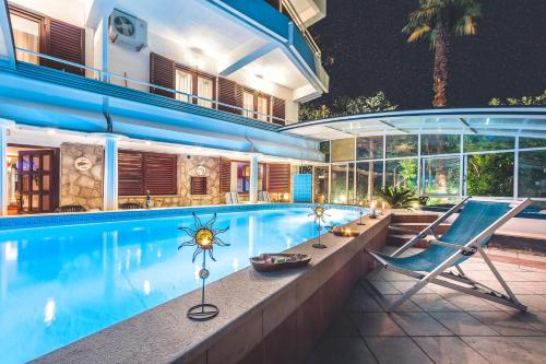 a house with a swimming pool and a chair at Villa Roses Apartments & Wellness in Ičići