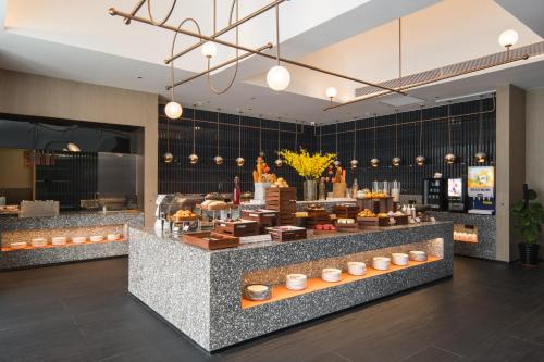 a bakery with a counter with food on it at Arthur Hotel Liwan COCO Park Dongsha Metro Guangzhou-24H Coffee & Low Tea & Free Shuttle Bus For Canton Fair By Paco in Guangzhou