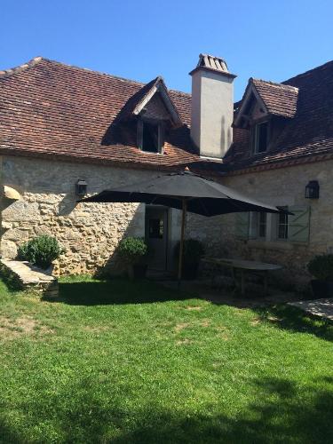 a building with an umbrella in front of a yard at Le Mas de Laval in Saint-Cirq-Lapopie
