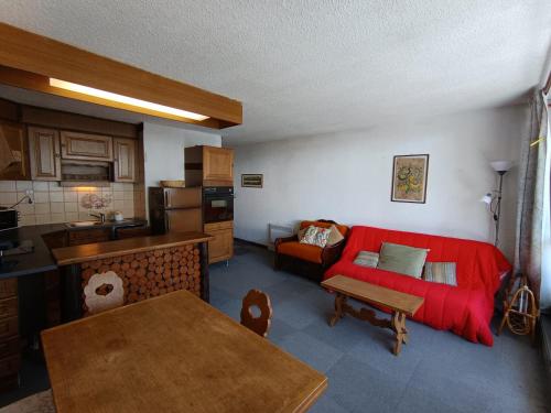 un salon avec un canapé rouge et une cuisine dans l'établissement Appartement face aux pistes - Animaux acceptés - FR-1-445-222, à Montgenèvre