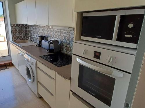 une cuisine avec un micro-ondes et une cuisinière four supérieur dans l'établissement Spacieux Appartement T3 avec Terrasse Ensoleillée et Parking - FR-1-494-211, à Royan