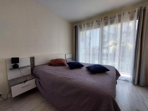 - une chambre avec un lit avec deux oreillers et une fenêtre dans l'établissement Spacieux 2 pièces avec balcon et parking proche gare, Royan - FR-1-550-93, à Royan
