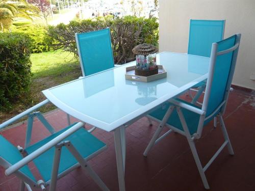 - une table blanche et 2 chaises bleues sur la terrasse dans l'établissement Bel appartement avec terrasse pour 4 personnes, proche plage à Port Camargue - FR-1-731-140, au Grau-du-Roi