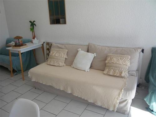 - un canapé blanc avec des oreillers dans l'établissement Bel appartement avec terrasse pour 4 personnes, proche plage à Port Camargue - FR-1-731-140, au Grau-du-Roi