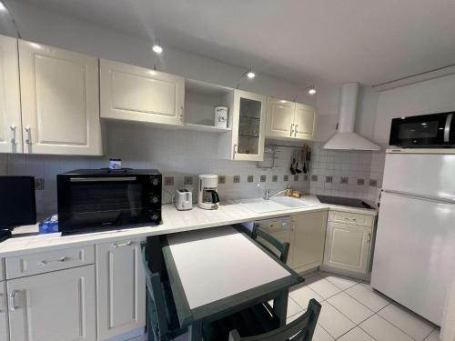 La cuisine est équipée de placards blancs et d'un four micro-ondes noir. dans l'établissement Pavillon 2 Pièces avec Terrasse, Piscine et Parking à 600m de la Plage - FR-1-701-92, à Vendres