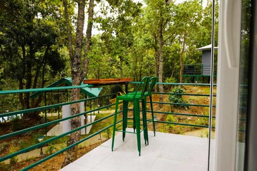 a green chair sitting on top of a balcony at Deodar I Luxury Tent Retreat in Majkhali in Chaubattia