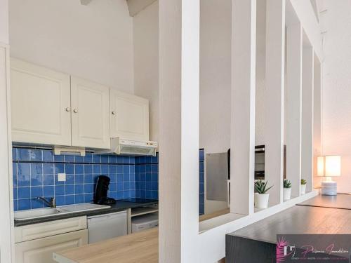 Il comprend une cuisine avec des placards blancs et un mur carrelé bleu. dans l'établissement Studio confortable à La Rochelle avec balcon - FR-1-825-68, à La Rochelle