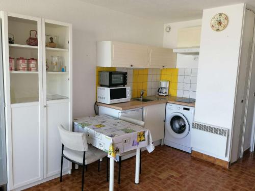une petite cuisine avec une table et un lave-linge. dans l'établissement Studio+Cabine avec Parking, Vue Port - FR-1-731-139, au Grau-du-Roi