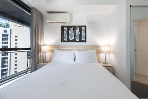 a bedroom with a large white bed and a window at Private CBD Bedroom in a Shared Apartment on Brisbane River in Brisbane