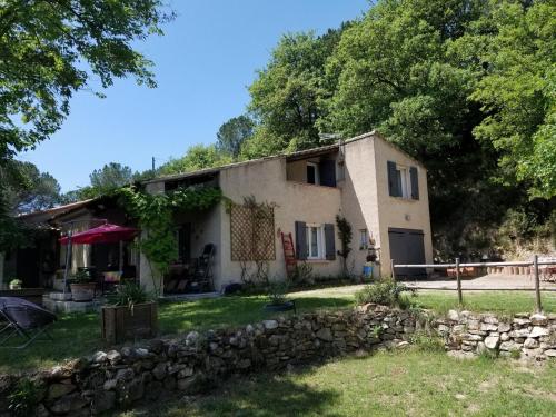 a house with a stone wall in the yard at Les Marronniers Charmant petit appartement a La Tour d'Aigues Vaucluse in La Tour-dʼAigues
