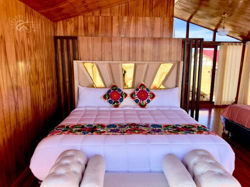 a bedroom with a white bed with two pillows at Titicaca Origins Perú in Puno