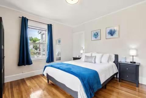 a bedroom with a large bed with blue curtains at Brighton 2 bedroom in Boston
