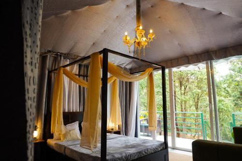 a bedroom with a canopy bed and a chandelier at Buransh Luxury Tent Retreat in Majkhali in Chaubattia