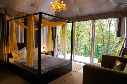 a bedroom with a canopy bed and a large window at Buransh Luxury Tent Retreat in Majkhali in Chaubattia