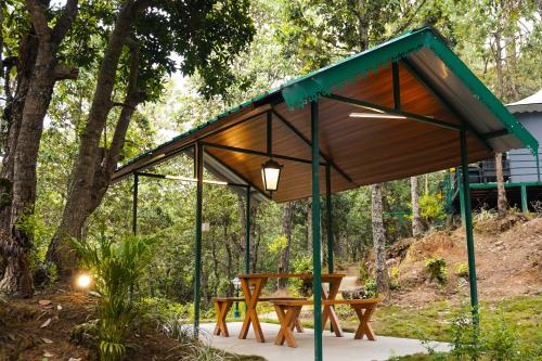 a pavilion with a picnic table in the woods at Buransh Luxury Tent Retreat in Majkhali in Chaubattia