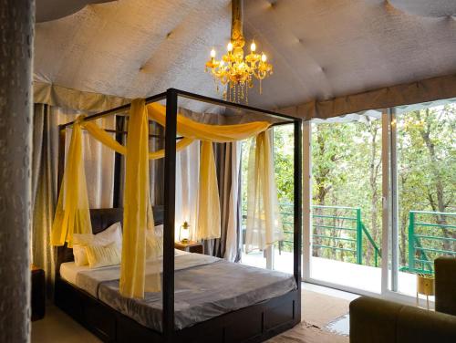a bedroom with a canopy bed and a chandelier at Four Luxury Tents in Majkhali in Chaubattia