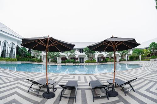 a group of chairs and umbrellas next to a pool at Indochina Hotel in Aranyaprathet