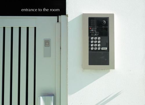 an entrance to the room with a remote control on a wall at ROOMs 003 カフェ併設 綺麗なワンルーム 分倍河原駅から徒歩3分 in Fuchu