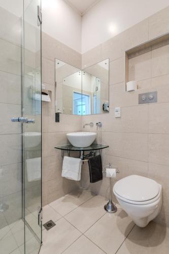 a bathroom with a toilet and a sink and a shower at George Street Motel Apartments in Dunedin