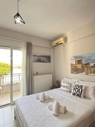 a bedroom with a large white bed and a balcony at Gerapetros 82 in Ierapetra