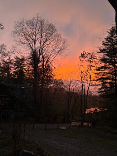 a sunset over a field with trees and a lake at Kartoffel in Kita-karuizawa