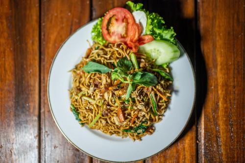 a plate of food with noodles and vegetables on a table at Yoga Maya Villa in Gianyar