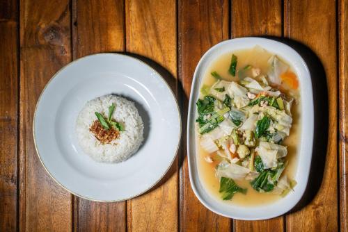 two bowls of soup and a bowl of rice on a wooden table at Yoga Maya Villa in Gianyar