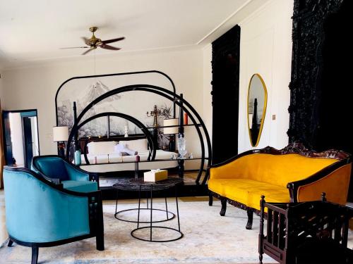 Un dormitorio con una cama y un sofá amarillo y sillas. en Helene's House - 5 Bedrooms Villa in Jl Bisma, Central Ubud, en Ubud