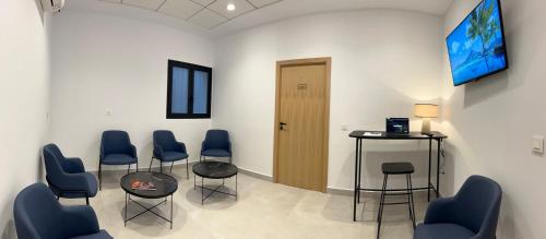 a waiting room with chairs and a table and a tv at Pensión La Orozca Benidorm in Benidorm