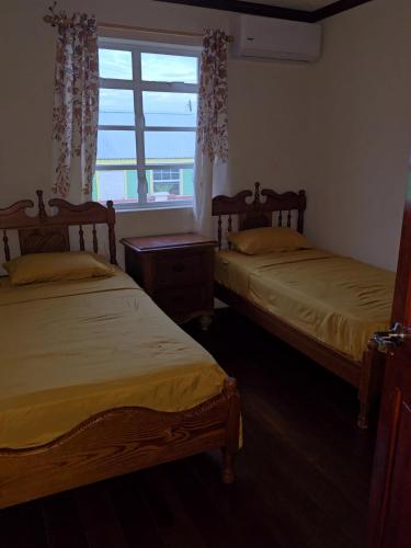 two beds in a room with a window at Historic Manor in Bridgetown