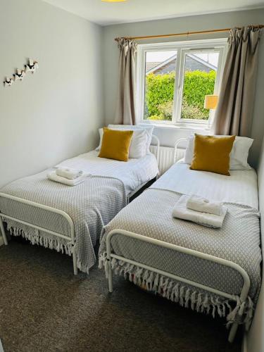 two twin beds in a room with a window at Moogara in Gorran Haven