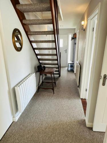 a hallway with a staircase with a bench and a table at Moogara in Gorran Haven