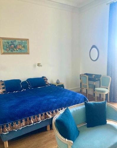 - une chambre avec un lit bleu, une table et des chaises dans l'établissement Château de Puycharnaud, à Lacaud