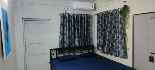 a bedroom with a bed with blue sheets and curtains at The Grasshopper's nest in kolkata
