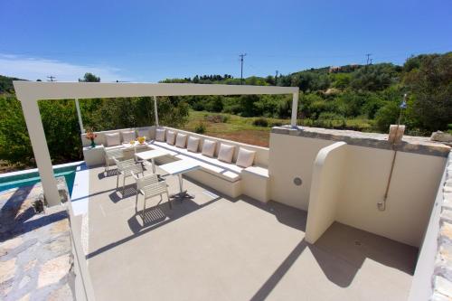 a patio with a table and chairs next to a pool at Magnolia Apartments in Fiskardho