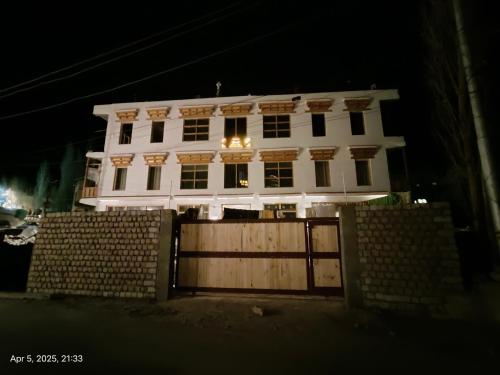 a white house with a fence in front of it at Honey Bee in Leh